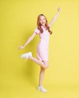 Full length image of young Asian girl standing on yellow background photo