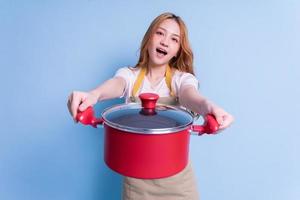 Image of young Asian woman holding pot on blue background photo