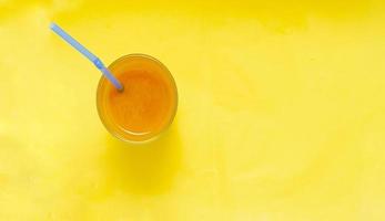 A Glass of Cool pumpkin juice with straw on pastel yellow background. photo