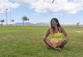beautiful latin woman 40 years old, smiling sitting on the grass of a park in Mallorca, balearic islands, hollidays concept photo