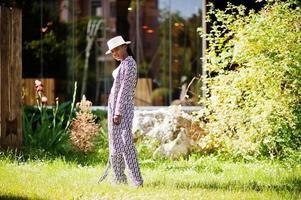 Hermosa mujer afroamericana con maquillaje natural, ropa de moda, ropa informal en blanco y negro, código de vestimenta, estilo de oficina, blusa y pantalones, traje y sombrero. foto