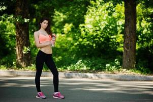 Fitness sport girl in sportswear posed at road in park with bottle of water, outdoor sports, urban style. photo