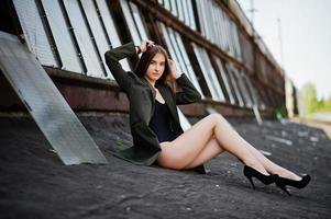 Sexy model girl wit long legs at black lingerie outfit body swimsuit combidress and jacket posed at the roof of abadoned industrial place with windows. photo