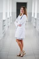 retrato de un joven médico atractivo con bata blanca con estetoscopio posando en el hospital. foto