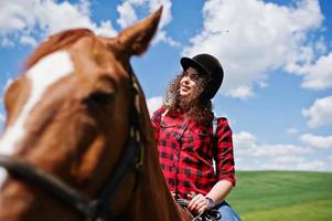 jovencita bonita montando un caballo en un campo en un día soleado. foto