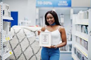 Portrait of a fabolous african american girl holding photo frame in the shop.