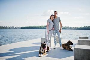 Couple in love with two dogs pit bull terrier against beach side. photo
