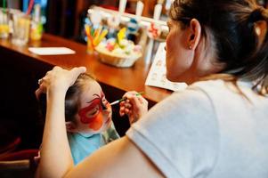 preparándose para el concepto de pascua. mujer haciendo maquillaje acuático para niña. foto