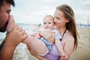 Summer vacations. Parents and people outdoor activity with children. Happy family holidays. Father, pregnant mother, baby daughter on sea sand beach. photo