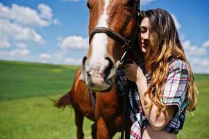 Young pretty girl stay with horse on a field at sunny day. photo