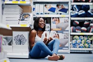 Impresionante joven afroamericana sentada en el suelo con cartas de amor en las manos en la tienda. foto