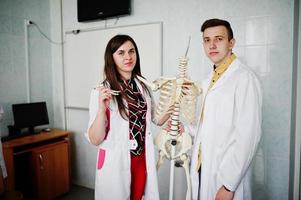 jóvenes médicos divirtiéndose posando con esqueleto. foto