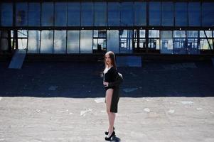 Sexy model girl wit long legs at black lingerie outfit body swimsuit combidress and jacket posed at the roof of abadoned industrial place with windows. photo