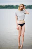 retrato de una modelo alta de aspecto fantástico con camiseta y bikini caminando en el lago. foto