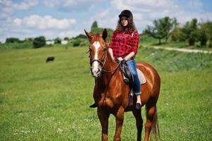 jovencita bonita montando un caballo en un campo en un día soleado. foto