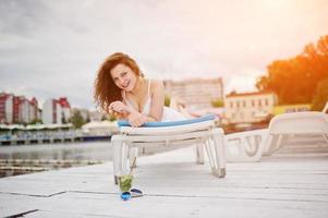 Portrait of a very beautiful girl laying and posing on a launger on a lakeside. photo