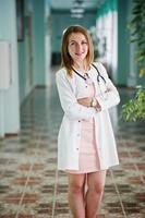 retrato de un joven médico atractivo con bata blanca con estetoscopio posando en el hospital. foto