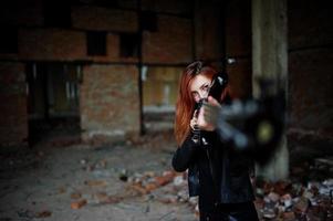 Chica punk pelirroja vestida de negro con bajo en un lugar abandonado. retrato de mujer gótica músico. foto