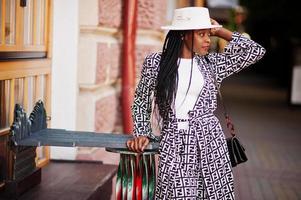 Beautiful african american woman natural makeup wear fashion clothes casual black and white dress code office style total blouse and pants suit and hat. photo
