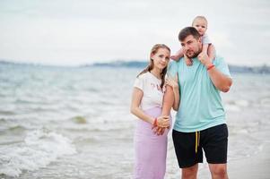 Summer vacations. Parents and people outdoor activity with children. Happy family holidays. Father, pregnant mother, baby daughter on sea sand beach. photo