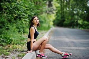 chica deportiva en ropa deportiva descansando en un parque verde después de entrenar en la naturaleza. un estilo de vida saludable. foto