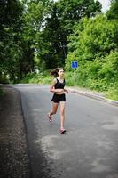 Sport girl at sportswear running in a green park and training at nature. A healthy lifestyle. photo