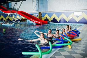 Fitness group of girls doing aerobical excercises in swimming pool at aqua park. Sport and leisure activities. photo