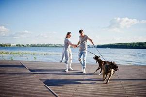 Couple in love with two dogs pit bull terrier against beach side. photo