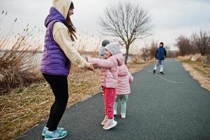 Mother with kids jump and having fun on the path by the lake. photo