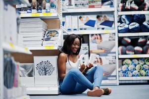 Stunning young african american woman sitting on the floor with love letters in her hands in the store. photo