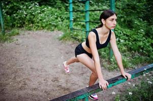 chica deportiva en ropa deportiva haciendo ejercicio en ejercicios de barra horizontal en un parque verde y entrenando en la naturaleza. un estilo de vida saludable. foto