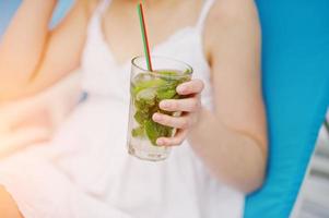 Close-up photo of a delicious mojito cocktail in a hand of a beautiful girl.