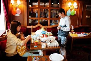 Preparing to Easter concept. Kids with mother making by hands bunny and eggs. photo