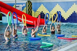 Fitness group of girls doing aerobical excercises in swimming pool at aqua park. Sport and leisure activities. photo