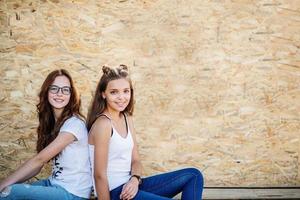 Portrait of a beautiful girl sitting on wooden boards against veneer wall. photo