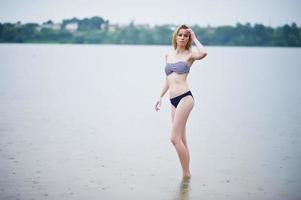 Portrait of a beautiful bikini model standing and posing in the water. photo