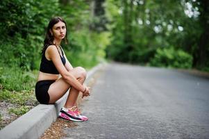 chica deportiva en ropa deportiva descansando en un parque verde después de entrenar en la naturaleza. un estilo de vida saludable. foto