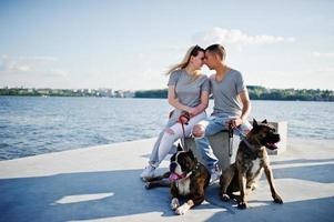 Couple in love with two dogs pit bull terrier against beach side. photo