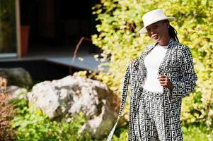 Beautiful african american woman natural makeup wear fashion clothes casual black and white dress code office style total blouse and pants suit and hat. photo