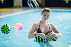 Close-up portrait of a smiling girls swimming in the pool with two balls looking like watermelons. photo