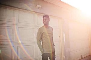 Portrait of an attractive black african american man posing and standing next to the garage gates. photo