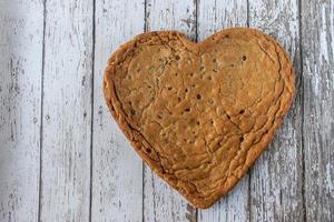 Huge Heart-shaped chocolate chip cookie on rustic wood table with copy space photo