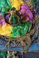 king cake with crown surrounded by mardi gras beads top view photo