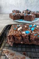 cut brownies with bright blue candy pieces and drizzled chocolate on top photo