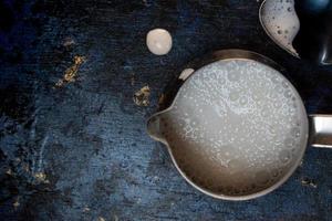 coffee creamer with frothed milk with bubbles on blue rustic background flat lay photo