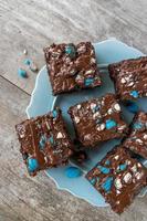 brownie squares with bright blue candy pieces and drizzled chocolate on top flat lay photo
