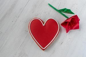 Red Heart-shaped cookie with icing and paper origami red rose on white background photo