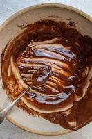 farmhouse bowl and spoon with remnants of brownie mixture flat lay photo