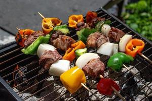 meat and vegetable kabobs over charcoal being grilled outdoors photo