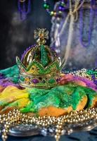 Colorful king cake with crown surrounded by mardi gras beads photo